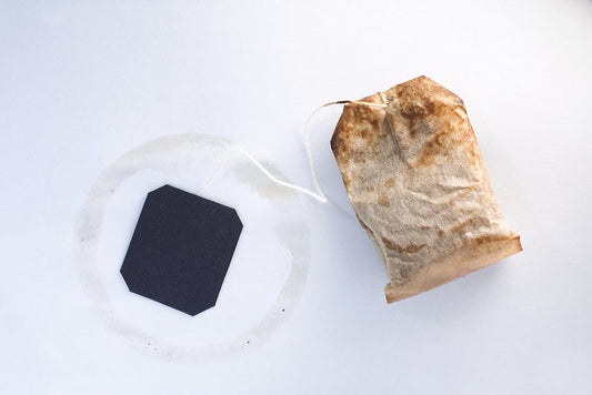 Close-up of a used tea bag with a black tag on a clean white background.