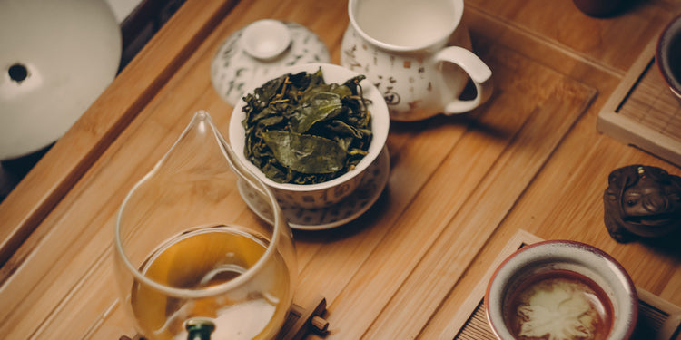 loose green tea leave with a cup of green tea on a bamboo serving tray